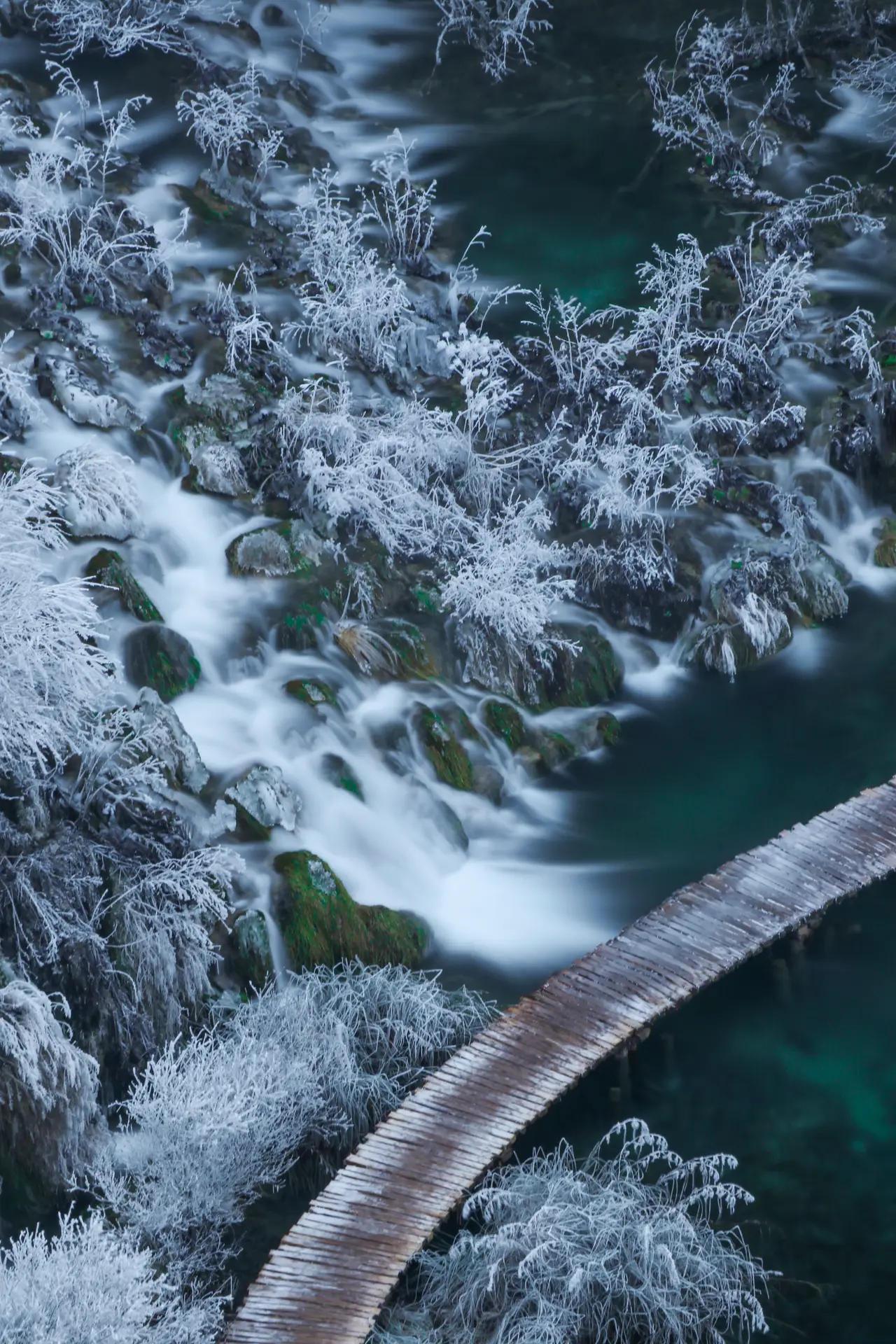 waterfall and lake and a woddoen trail covered in snow