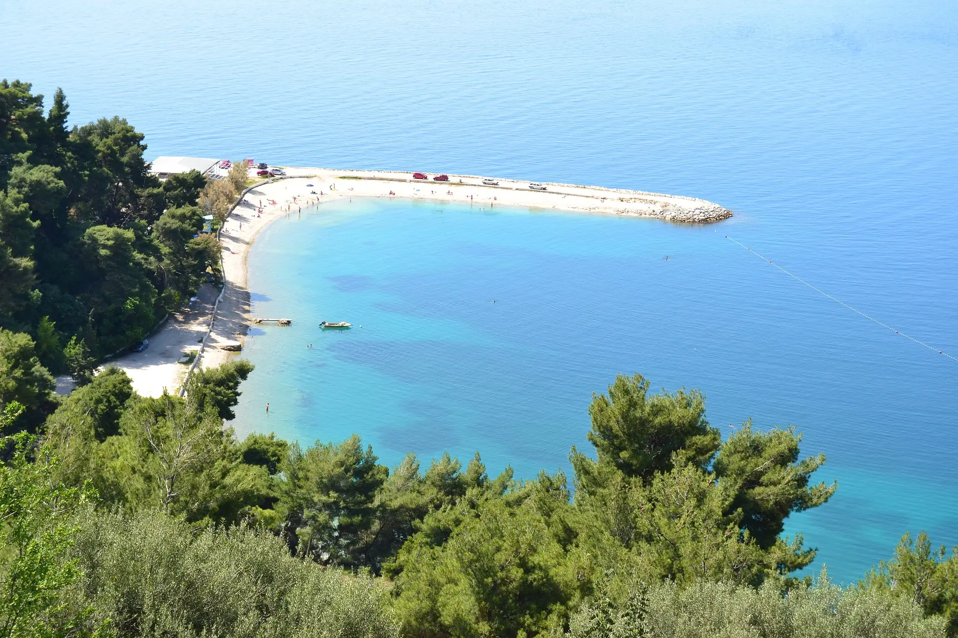 aerial view of a white beach featuring surrounding  forrest 