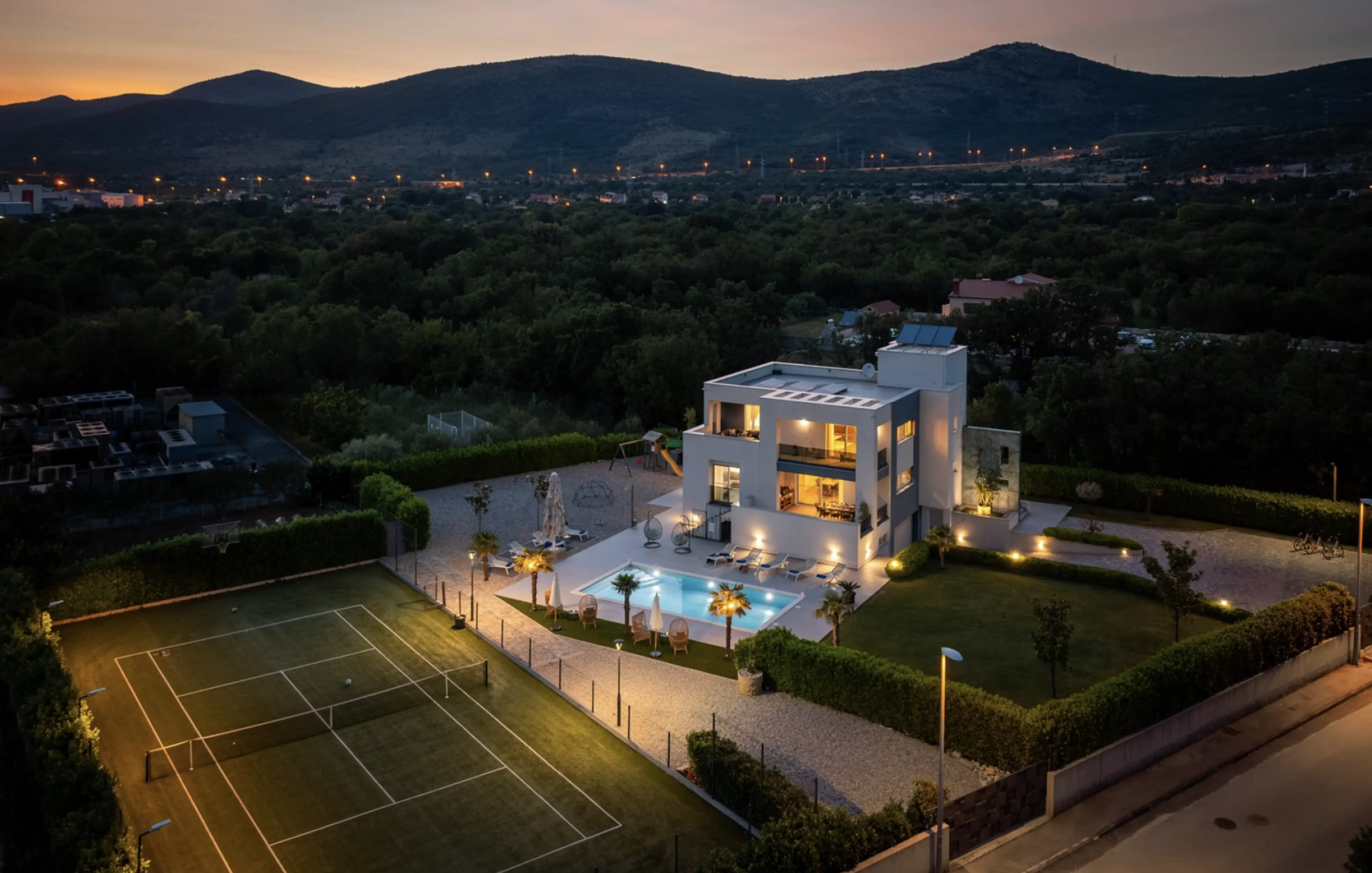 villa with pool and tennis court at night