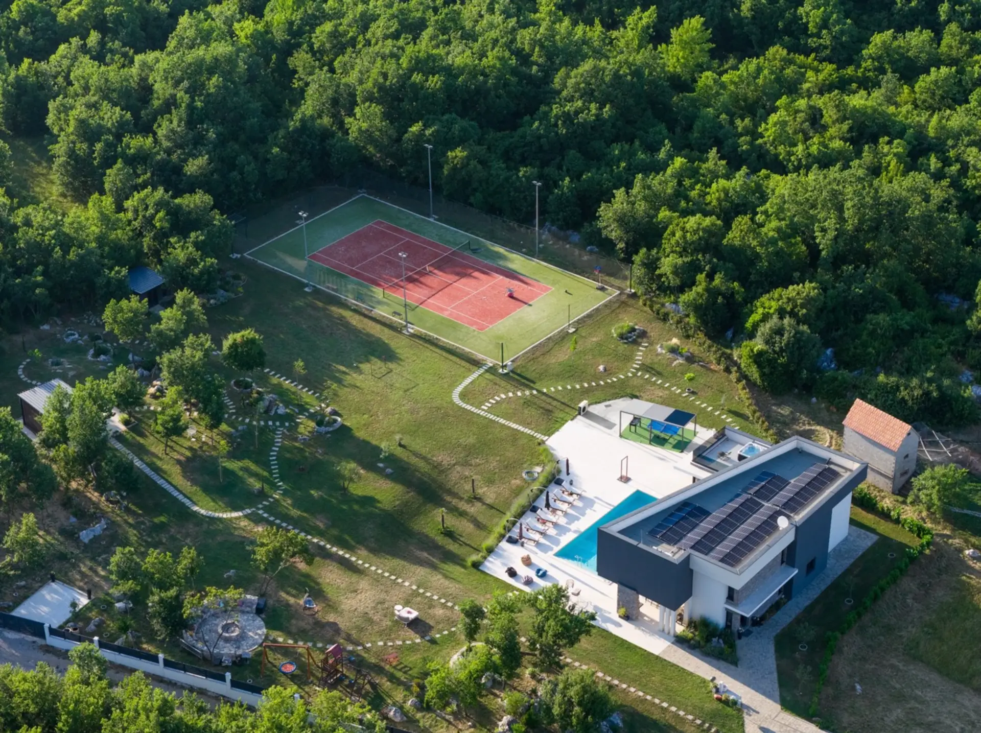 Luftaufnahme eines Anwesens mit Villa, Pool und Tennisplatz