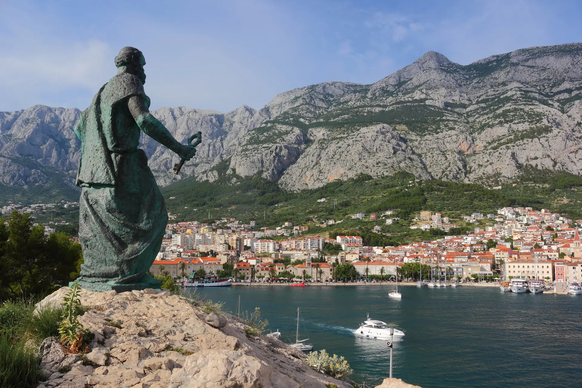 monument of a saint looking at the city across the sea 