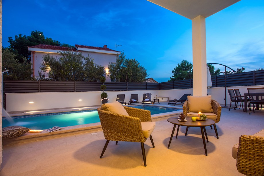 sitting area with view on the pool with a small waterfall and warm lights