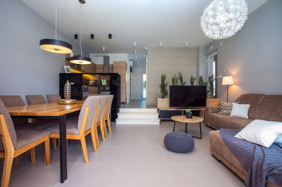 an open living system with dining table and 8 chairs, a living room and kitchen