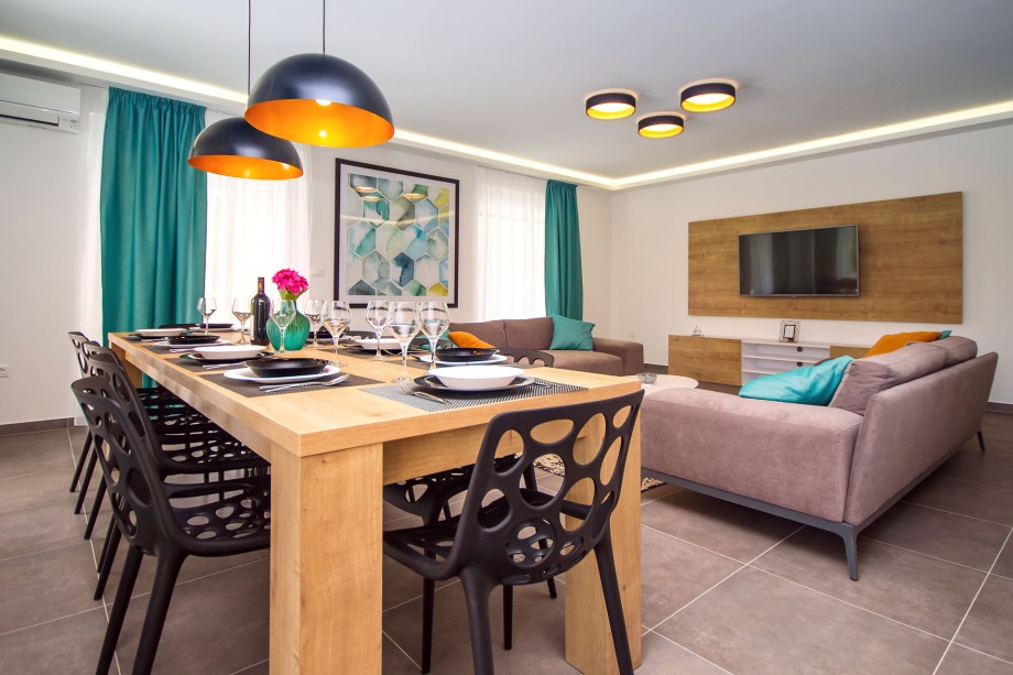 Dining room with a big table and comfortable chairs, living room with PS4