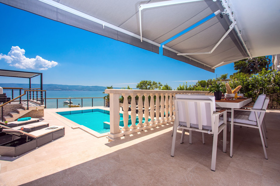 Outdoor dining area with sea and pool view, connected with a kitchen
