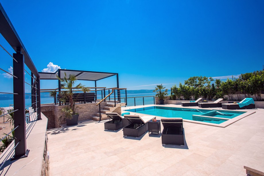 Pool area with sun deck area, outdoor shower, sitting area and exit to the beach