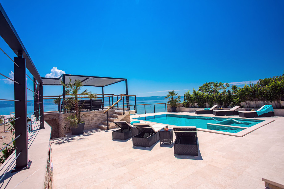 Pool area with sun deck area, outdoor shower, sitting area and exit to the beach