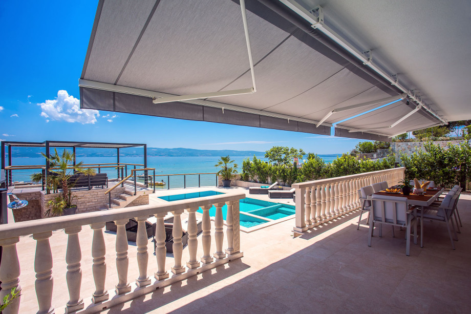Outdoor dining area with sea and pool view, connected with a kitchen