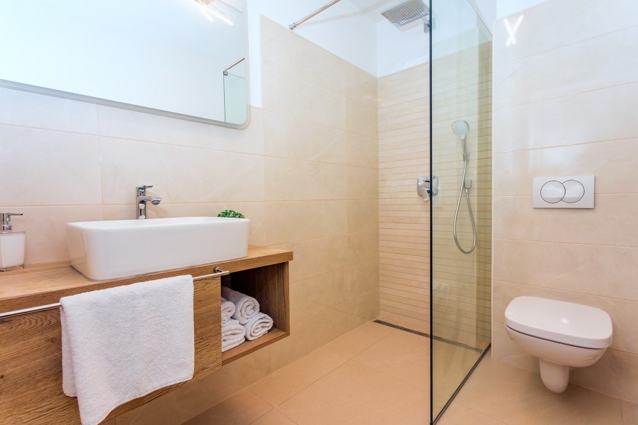 family bathroom with a shower and a laundry room with a washer next to the entrance