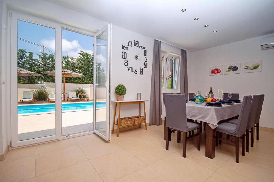 Living room and dining area with exit to pool area, all is air-conditioned