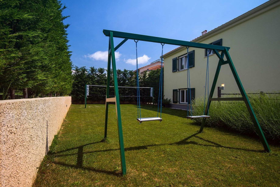 Playground behind the house with a badminton net and 2 swings