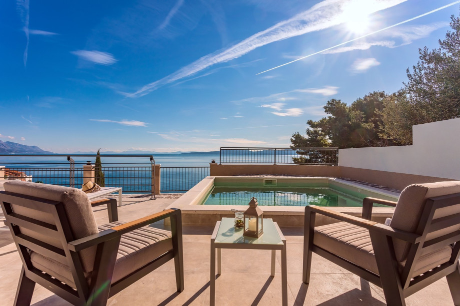 A sitting area by the pool and jacuzzi with sea view
