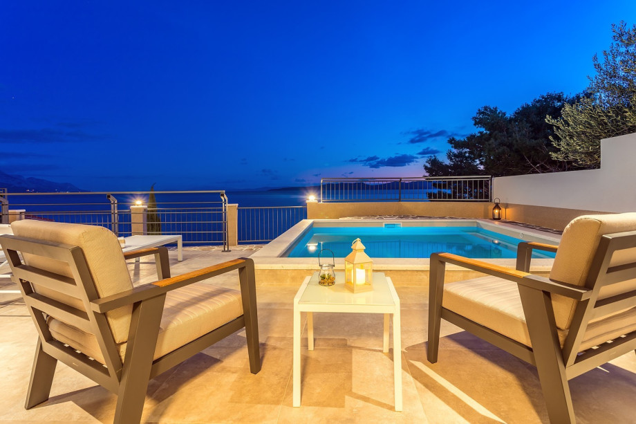 Siting area by the pool in the night and a view at the sea and islands