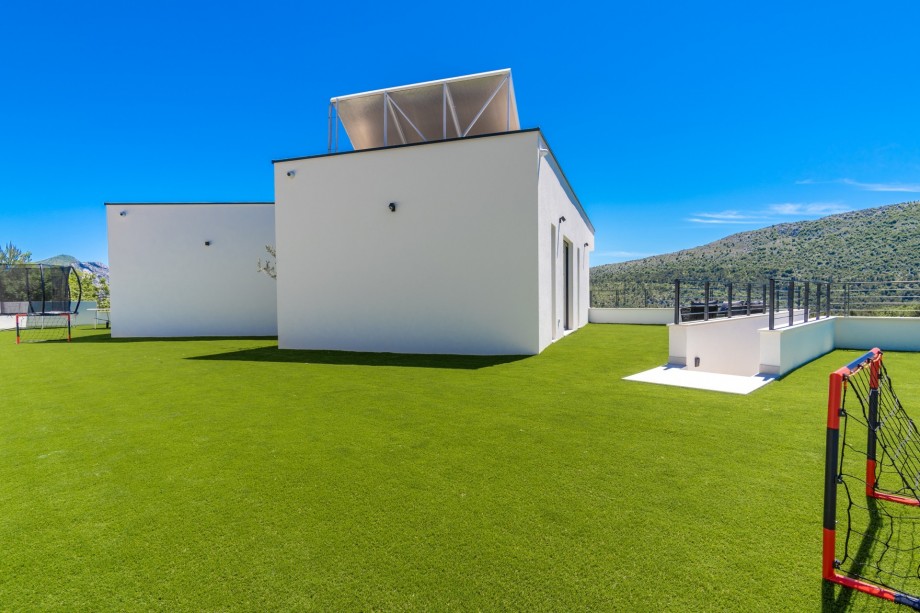 Behind the house, there is an artificial grassplot