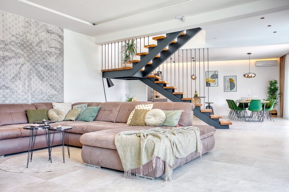 The living room with a flat-screen TV, glass walls toward the pool area