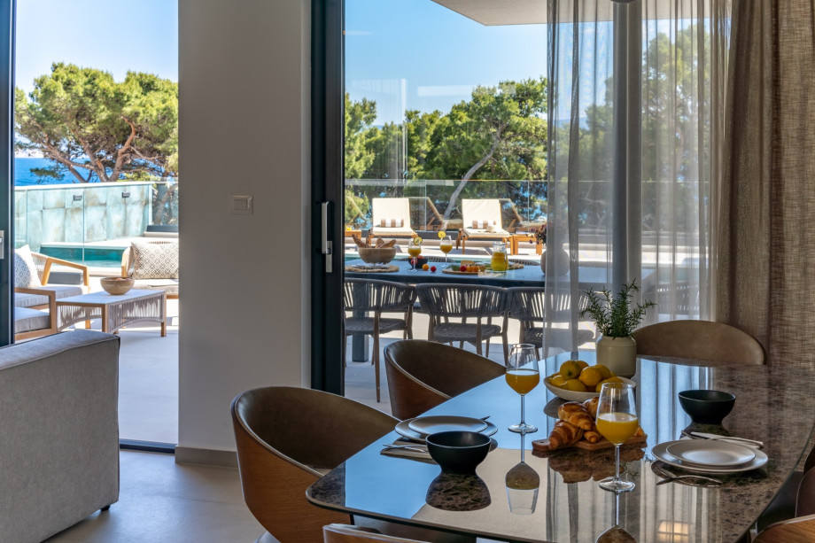 A dining area with a glass door toward the pool area and direct exit to the covered outdoor dining area