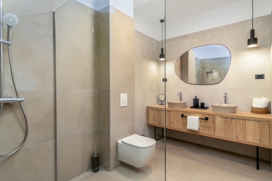 An en-suite bathroom with a shower, a double-sink, and a toilet