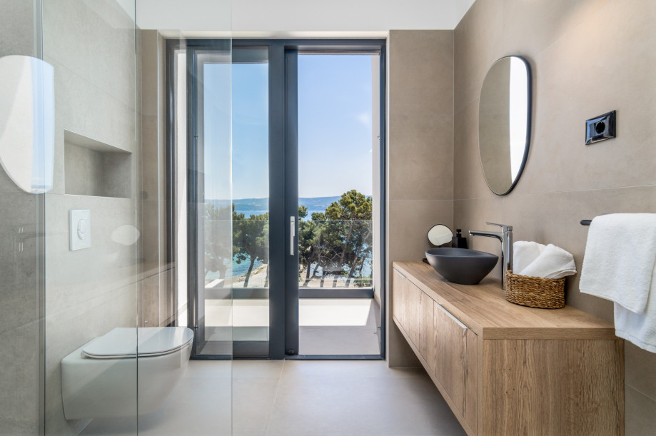 An en-suite bathroom with a shower, a sink, and a toilet with its own exit to the balcony