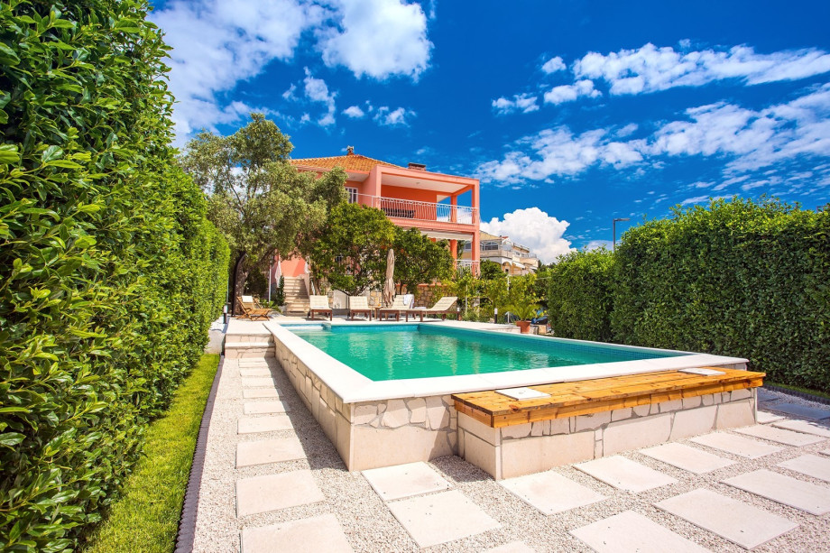 Pool area with green fence in front of the villa