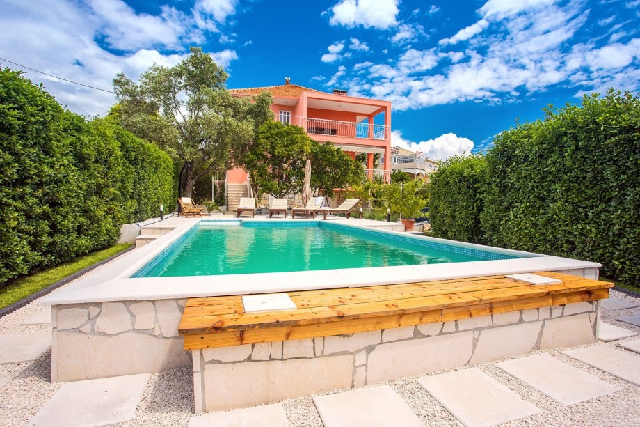 Pool area with green fence in front of the villa