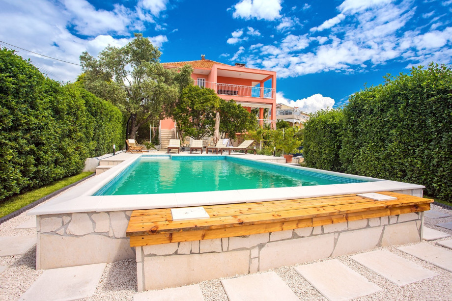 Pool area with green fence in front of the villa