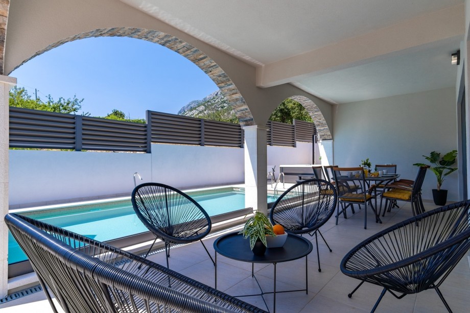 Lounge furniture next to the pool and outdoor dining area