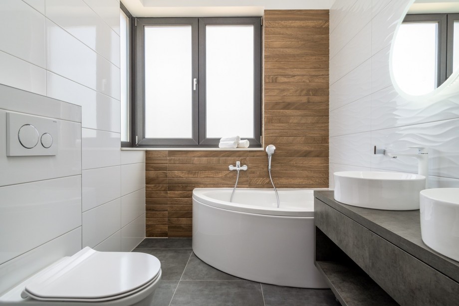 An en-suite bathroom with a bathtub, a double sink, and a toilet
