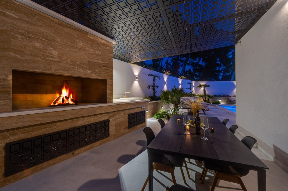 A covered outdoor dining area for 8 people with a traditional barbecue and a playground with basketball net and football nets