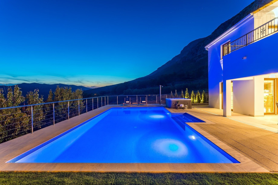 A night view on private swimming pool, Jacuzzi and covered outdoor dining area.