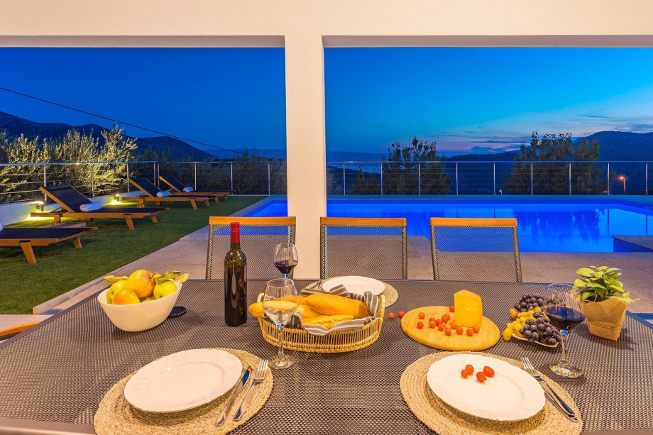 A night view on private swimming pool, and covered outdoor dining area.