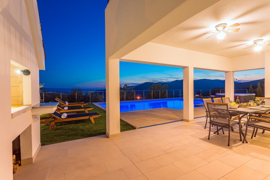 A night view on private swimming pool, Jacuzzi and covered outdoor dining area.
