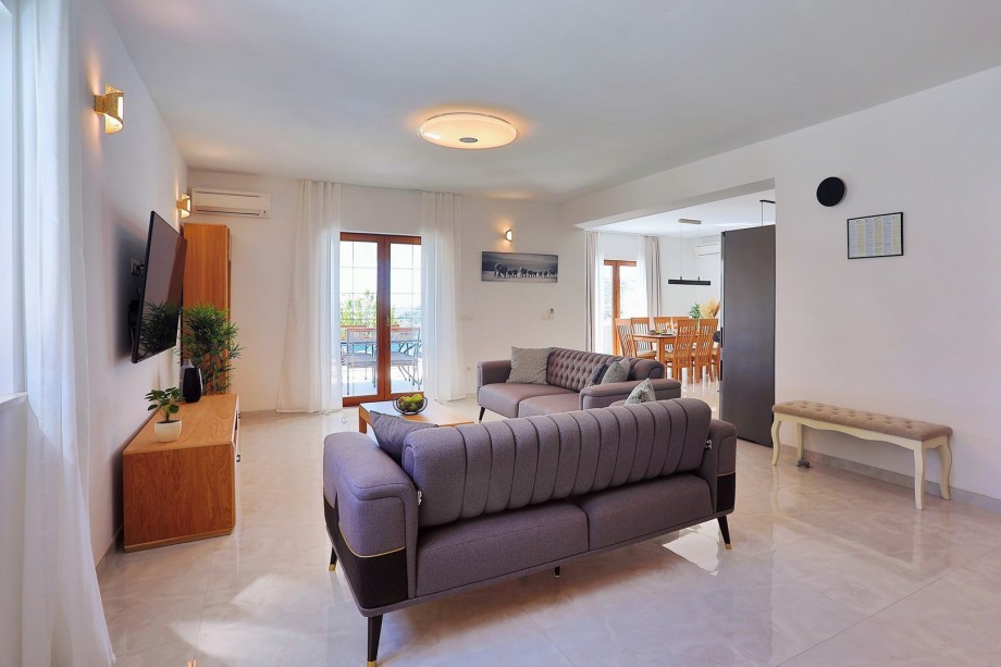 Living area with sofas, a smart TV with direct exit to the pool area and outdoor dining area