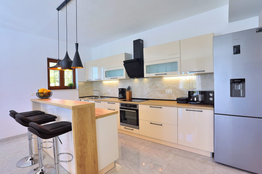 A Fully equipped kitchen with dining area and direct exit to the pool and outdoor dining area