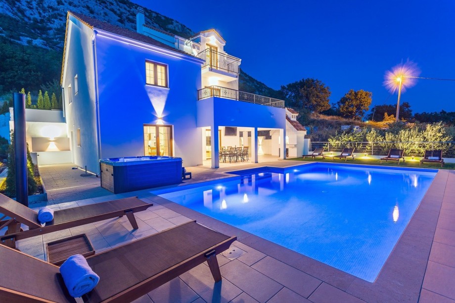 A night view on private swimming pool, Jacuzzi, covered outdoor dining area and traditional BBQ