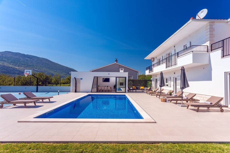 Private 40sqm heated pool with 8 lounge chairs, summer kitchen with bbq and dining area
