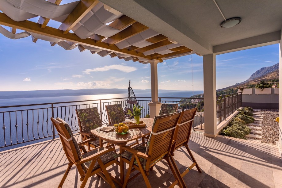 Covered outdoor dining area with gas barbecue  with panoramic sea and island views