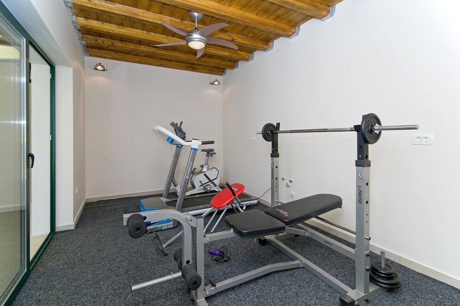 Fitness room with treadmill, bench with weights and exercise bike.