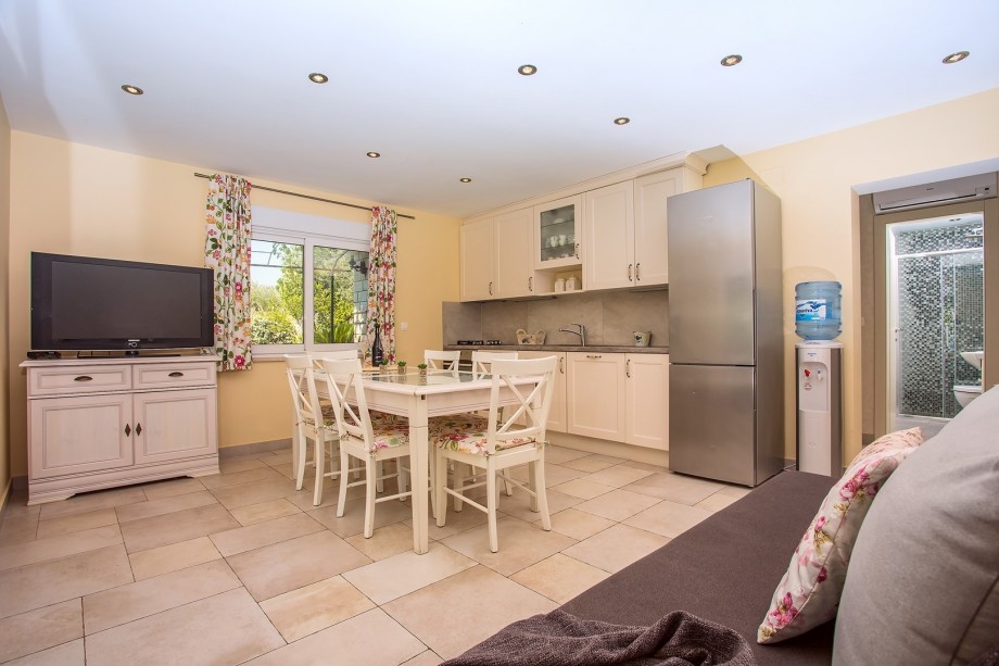 Air-conditioned and fully equipped kitchen with dining area, a sofa and a TV