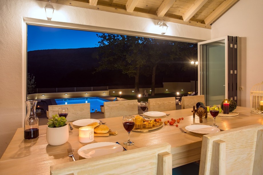 Dining area next to the fully equipped kitchen with view on the lighted pool