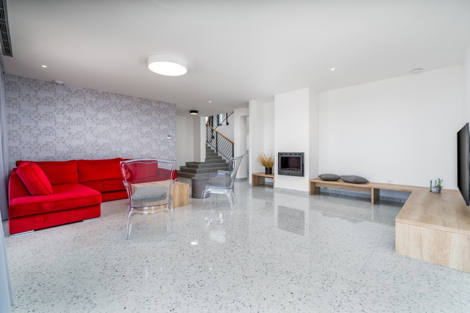 A spacious living room with LCD TV, USB Stereo system, Air-conditioner, a fireplace.