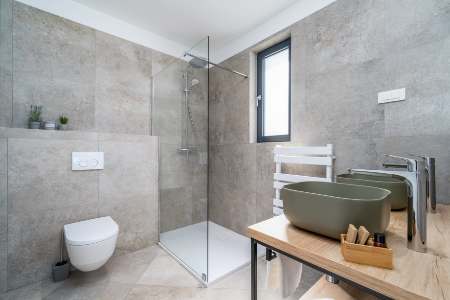 An en-suite bathroom with a shower, 2 sinks, and a toilet