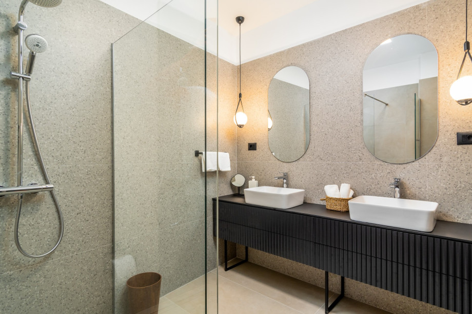 An en-suite bathroom with a shower, a double-sink, and a toilet