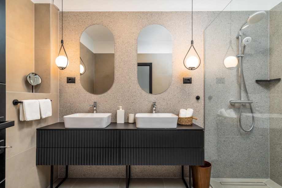 An en-suite bathroom with a shower, a double-sink, and a toilet