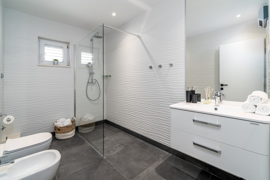 Family bathroom with a shower, toilet and a bidet, and another smaller family bathroom with a shower and a toilet