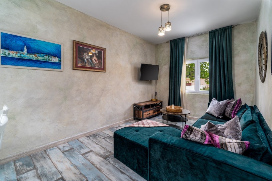 A living room with a sofa, Air-condition, and a flat-screen TV