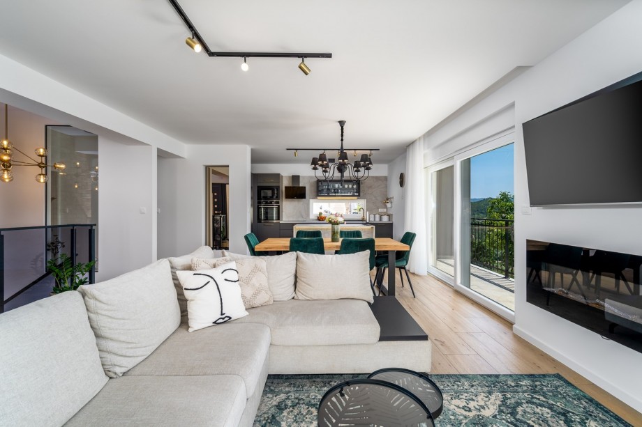 The living room with a flat-screen TV, glass walls toward the pool area