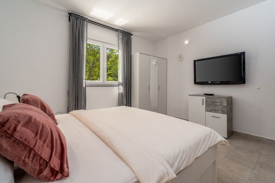 A Bedroom No1 with a king size bed 180cm x 200cm, air-condition, a TV and the views on the pool area.