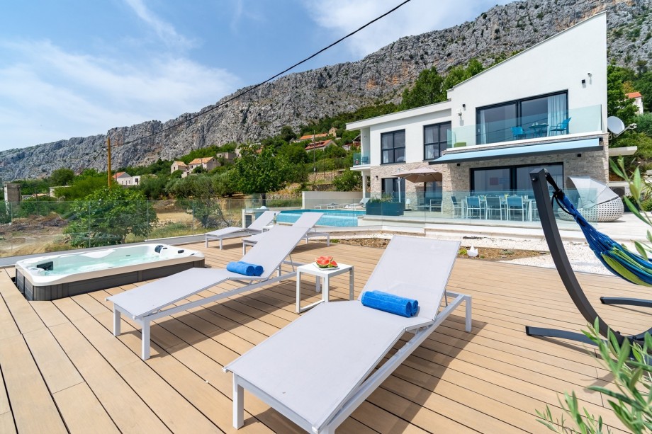 The outdoor offers a private and heated, infinity 32 sqm pool with a no-Chlorine system, a Hot Tub, two sun deck areas, 8 deck chairs, a cozy outdoor sofa, 1 sun umbrella, an outdoor shower