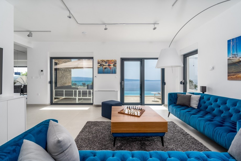 Living area with a comfortable sofa and exit toward the pool and the barbecue area