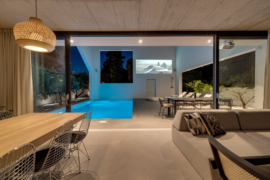 The ground floor (pool level) offers a fully air-conditioned and very spacious living and dining area with floor-to-ceiling glass doors toward the pool area.